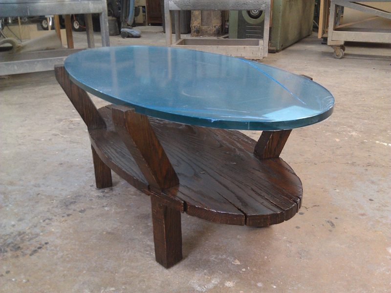 Oval glass-top coffee table with a dark wood base and lower shelf