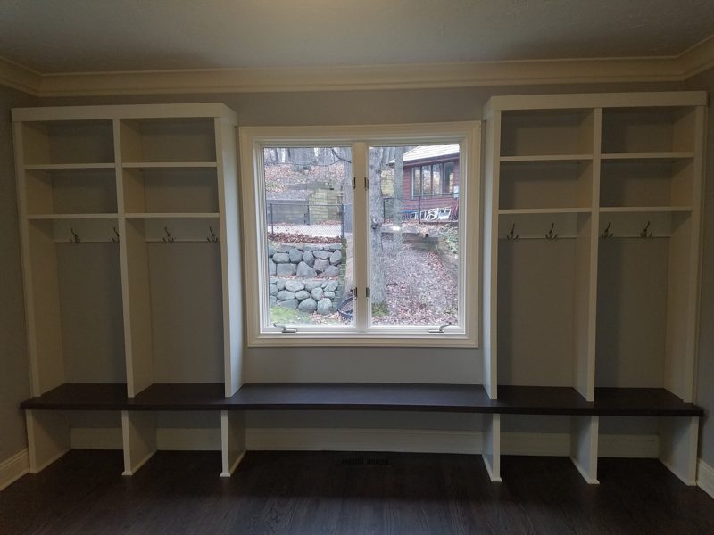 White lockers on both sides of a window with a long dark wood bench