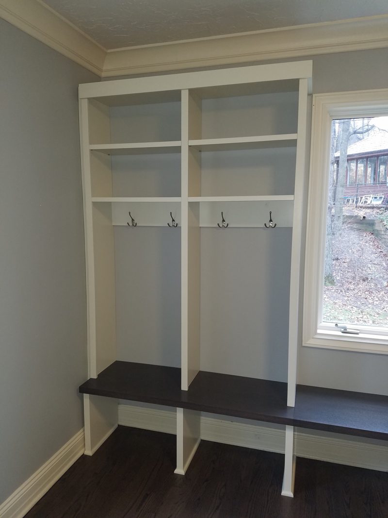 White mudroom lockers with hooks and a dark wood bench