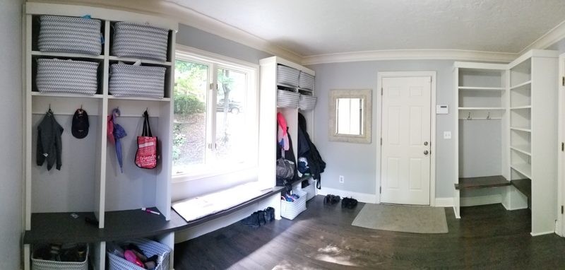White mudroom lockers with hooks and baskets beside a window bench