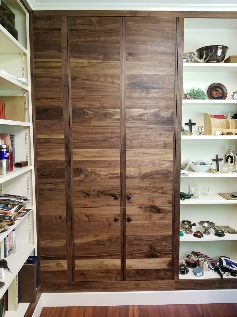 Tall dark wood plank cabinet doors beside white built-in display shelves