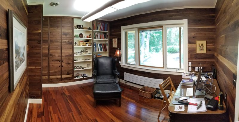 Wide view of a wood-paneled office with built-in shelves and a desk