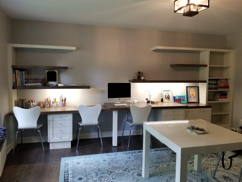 Home office with long white desks, floating shelves, and a table