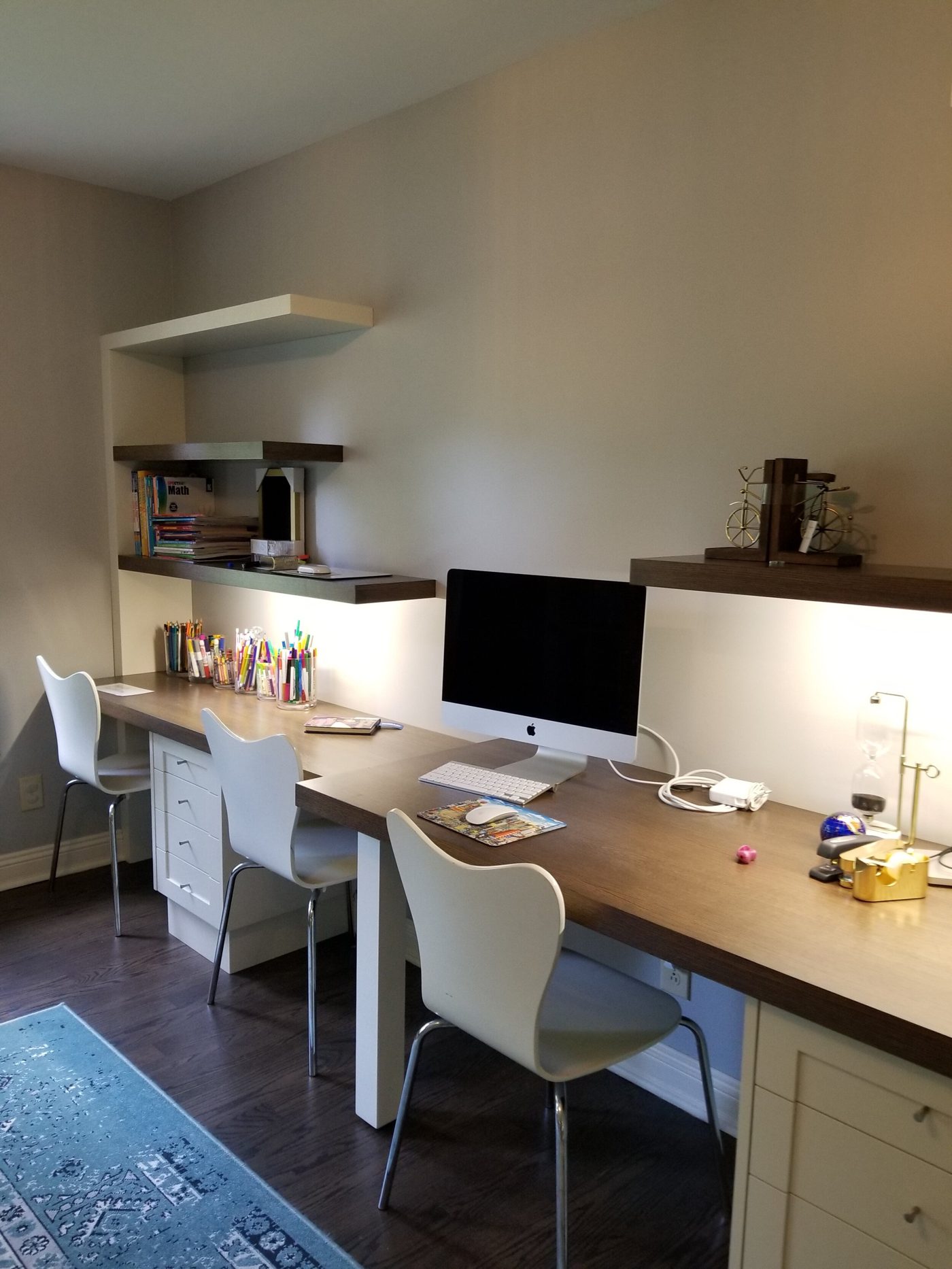 Home office with a curved dark-wood desk under a lamp and a built-in cabinet holding a television