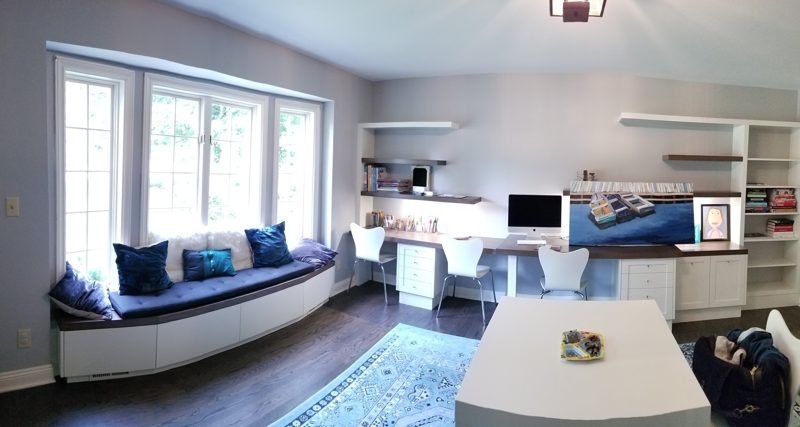 Office with a long built-in desk and a white window bench with cushions