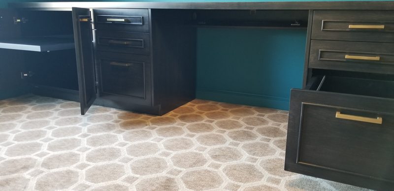 Open drawers on a dark built-in desk showing a file drawer and brass pulls