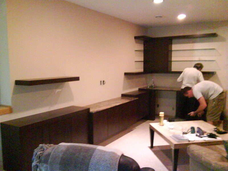 Dark built-in desk and shelves during installation in an empty room