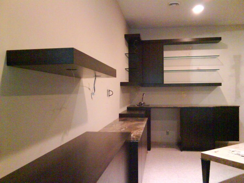 Dark wood floating shelves and wall desk being installed