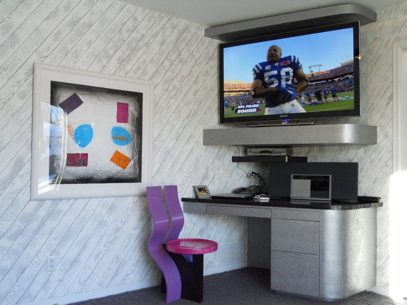 Wall-mounted TV above a gray desk with rounded drawers and a purple chair
