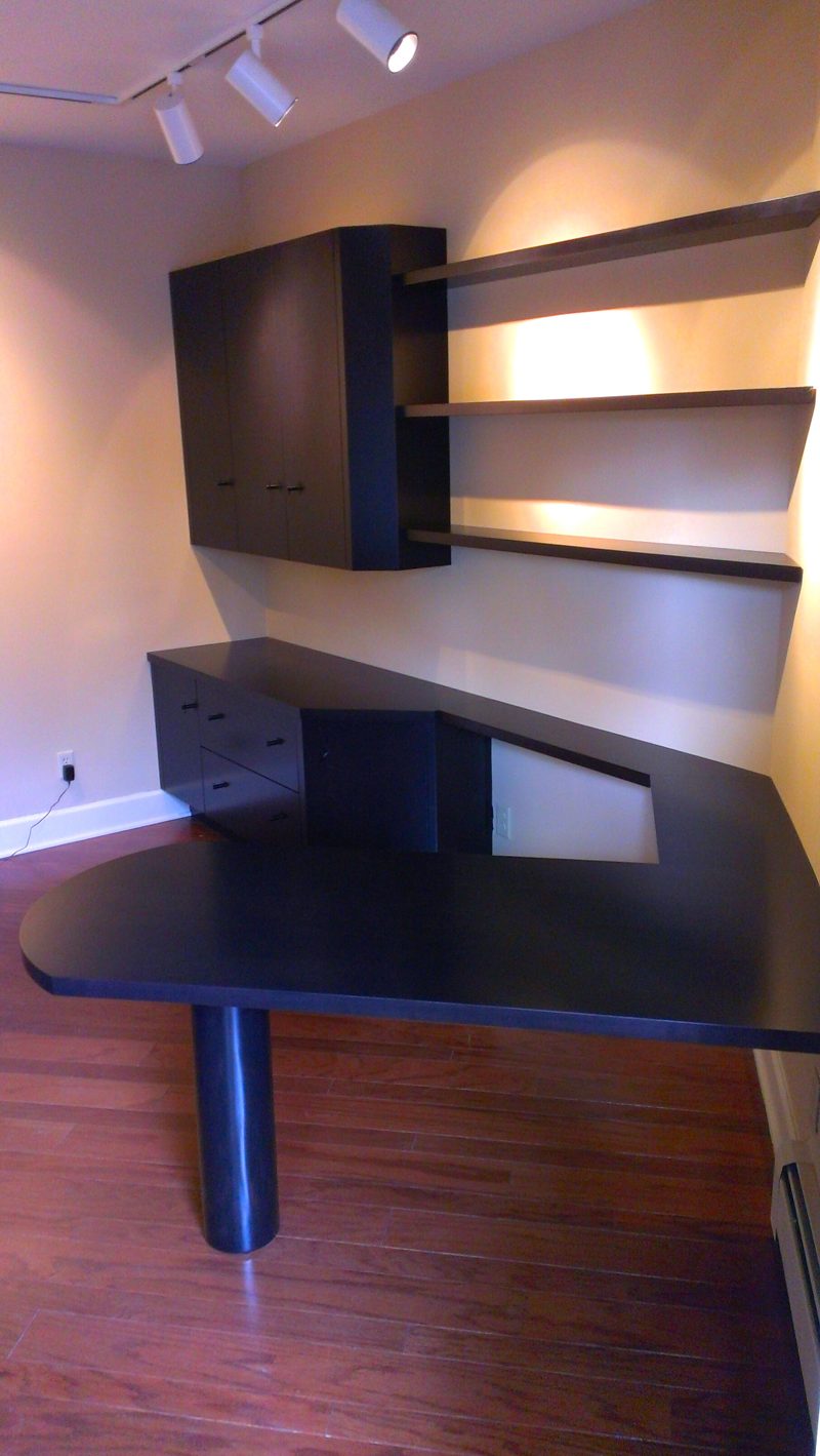 Black L-shaped desk with a round end and floating shelves