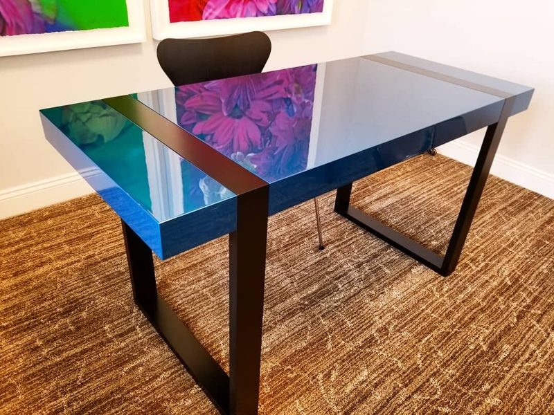 Angled view of a glossy blue desk with a dark inlay stripe