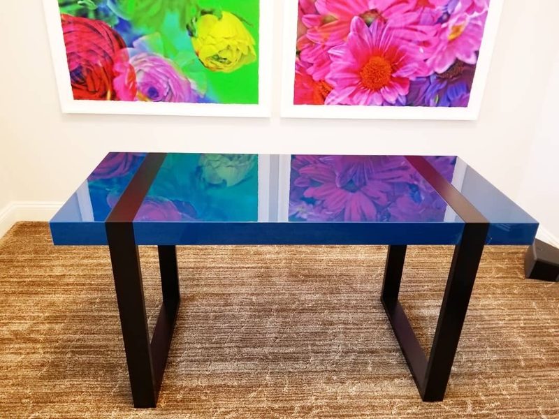 Desk with a glossy blue top, dark center stripe, and black trapezoid legs
